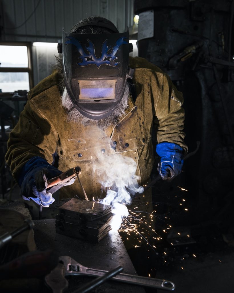 blacksmith-in-welding-mask-welding-metal-in-workshop.jpg